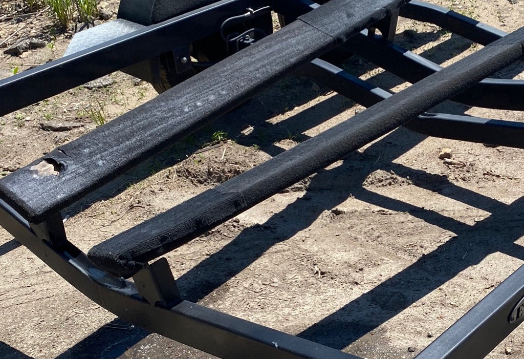Old boat trailer bunk carpet showing wear and trapped debris beneath a boat, highlighting the importance of boat trailer bunk maintenance.