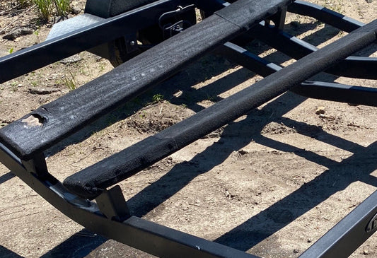 Old boat trailer bunk carpet showing wear and trapped debris beneath a boat, highlighting the importance of boat trailer bunk maintenance.